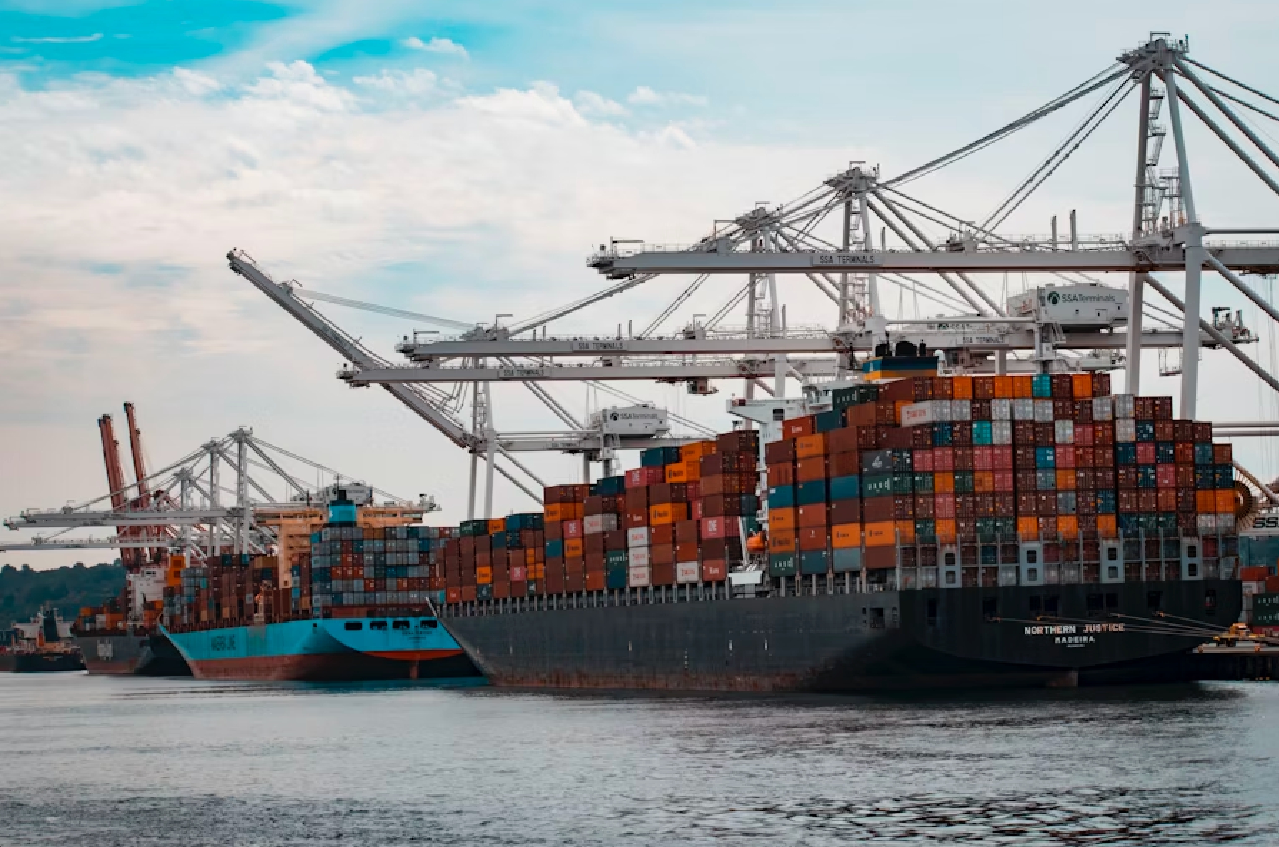 Cargo vessels loaded with shipping containers at a commercial port, representing international trade and logistics